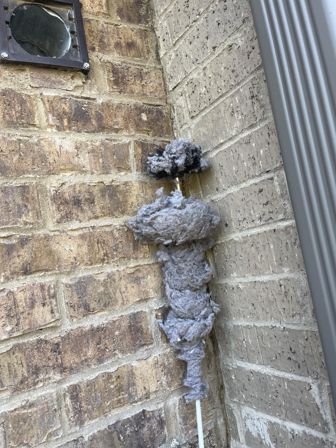Dryer vent lint caught on cleaning brush rod during service